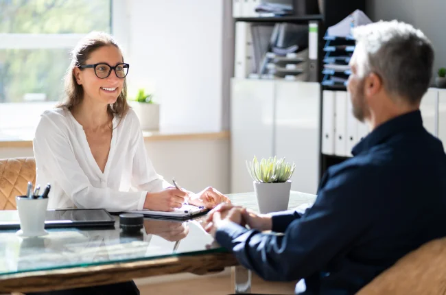 Freundliche Vorgesetzte bespricht sich mit einem Mitarbeiter am Schreibtisch